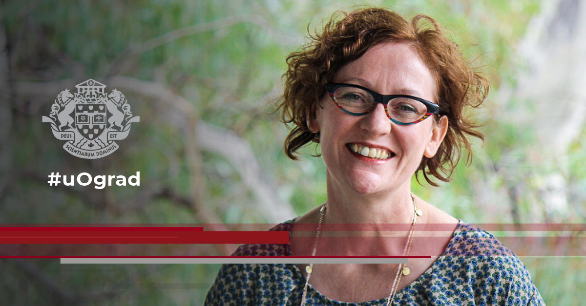 Siobhan smiles facing viewer in front of a green landscape