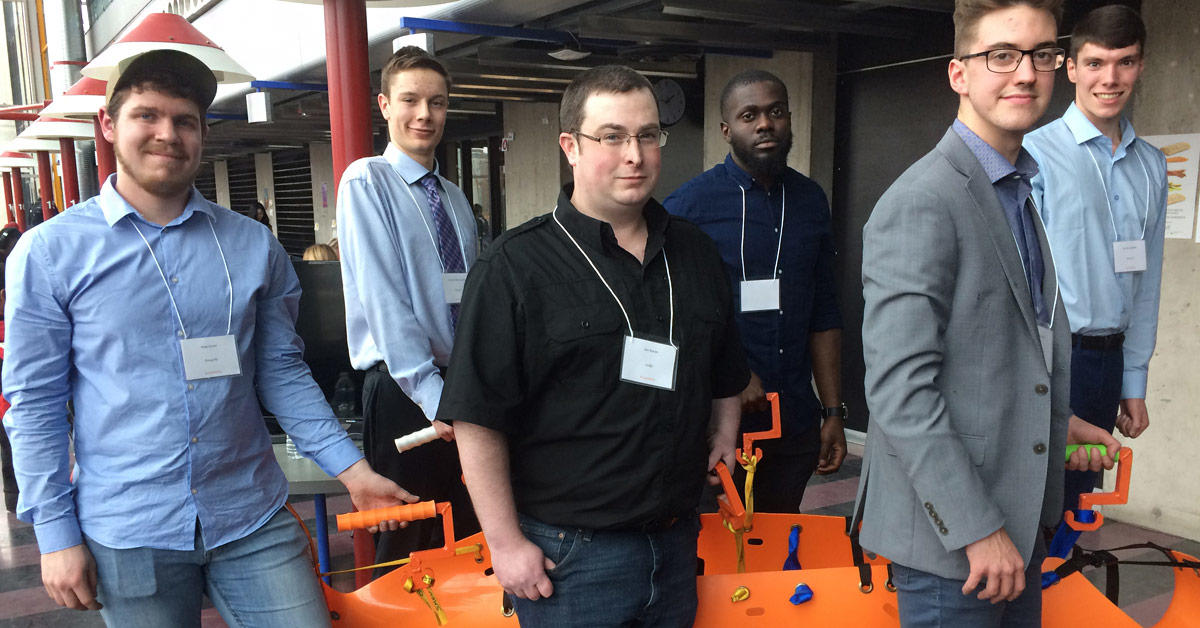 Six men smiling and holding a curved search and rescue sled.