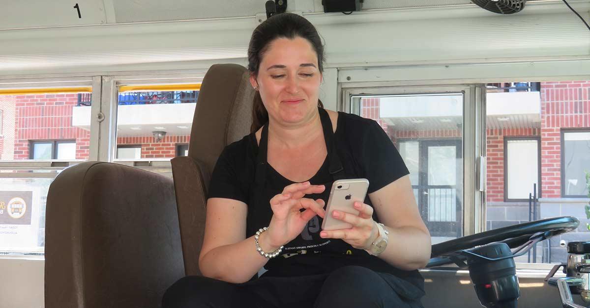 Anne Donovan regarde son cellulaire assise sur le siège du conducteur.