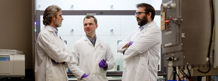 Three researchers stand together in a lab