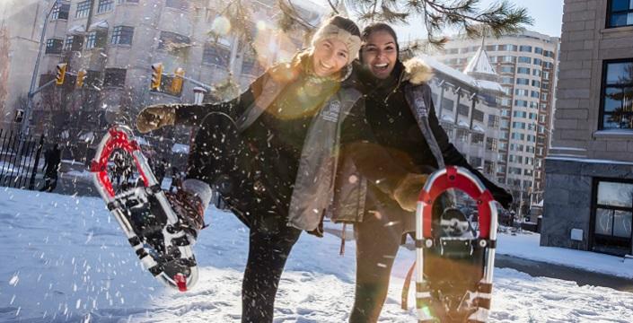 Two students having fun snowshoeing on the Tabaret Hall front lawn.
