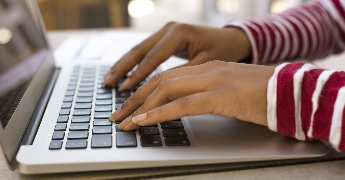 A woman's hands on a laptop keyboard.