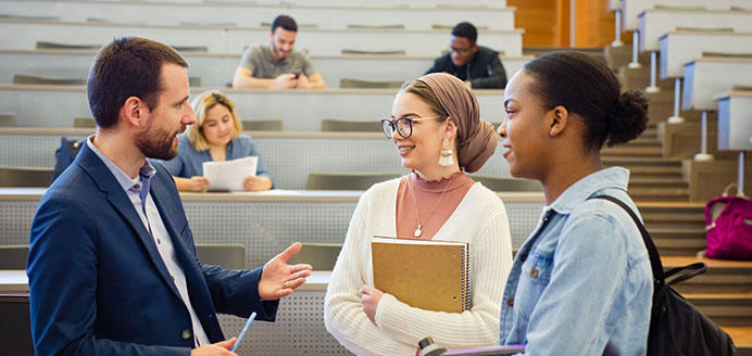 Un professeur qui parlen à des étudiantes dans une salle de classe.