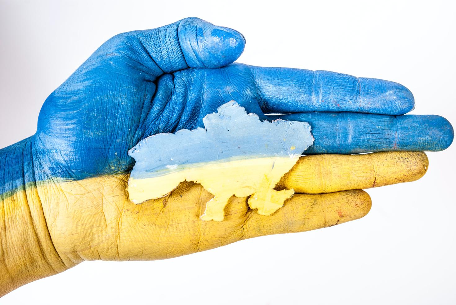 Main tenant un découpage de l'Ukraine peint aux couleurs du drapeau