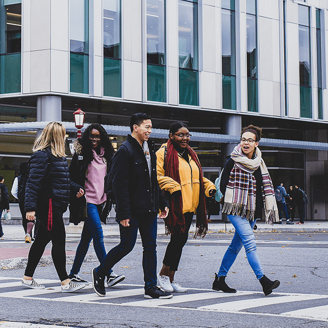 People walking across a crosswalk on campus