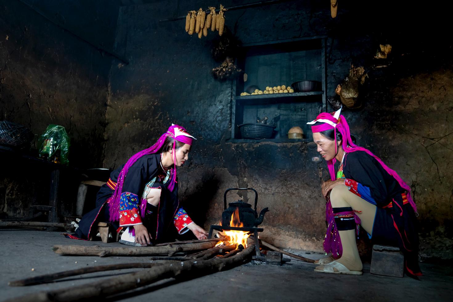 Two people using a traditional cooking hearth
