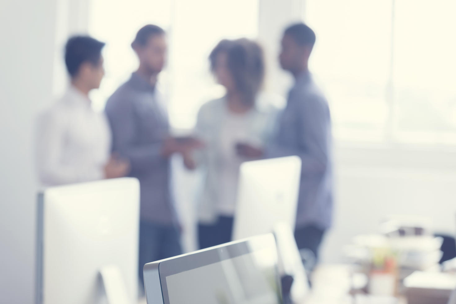 Blurred image of four collegues chating  