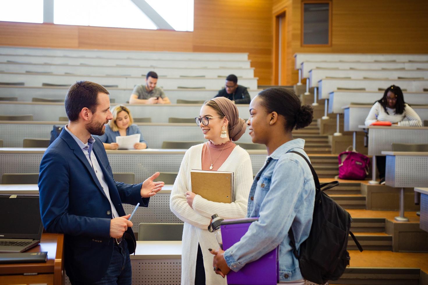 Professor in conversation with two students in graduate seminar