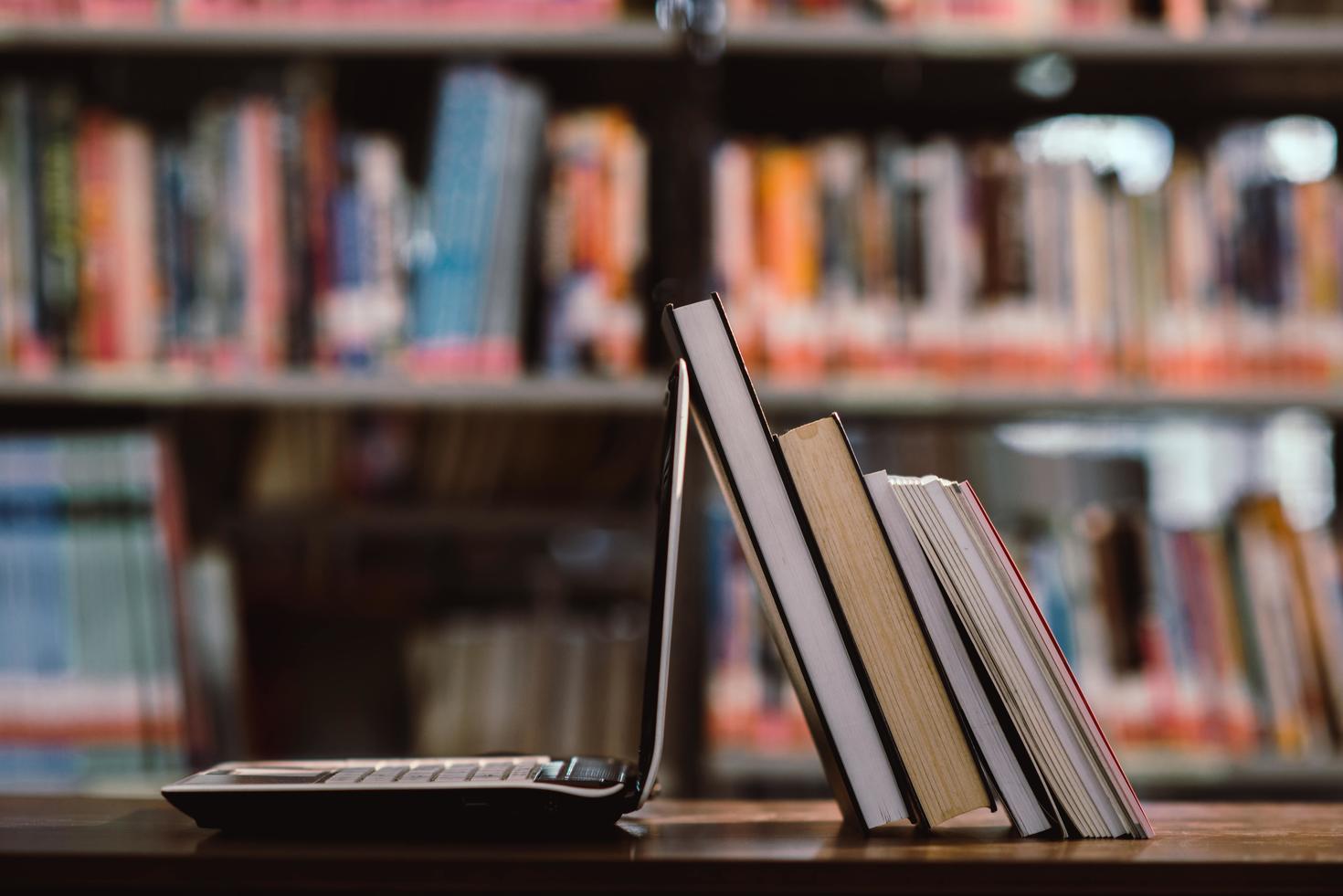 laptop computer and book on workplace at library room