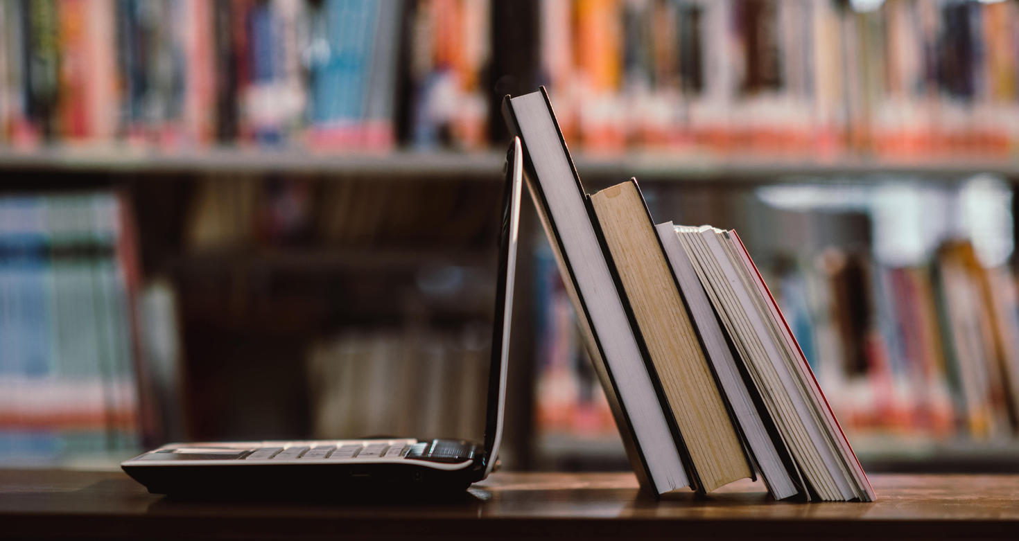 laptop and books at a workplace in library room