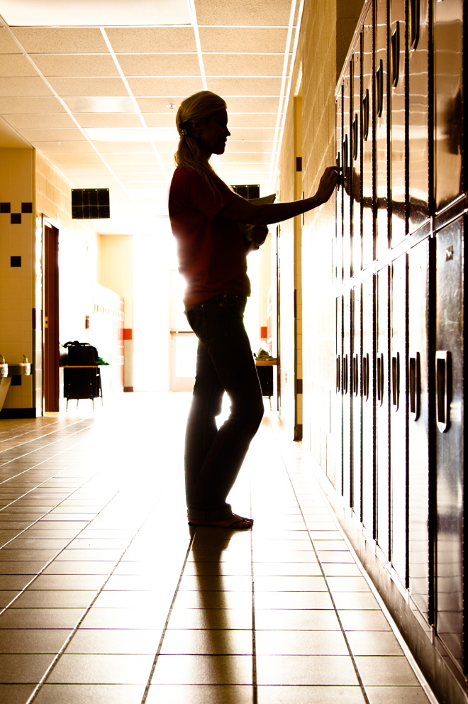 person standing at lockers in sunlit hallway