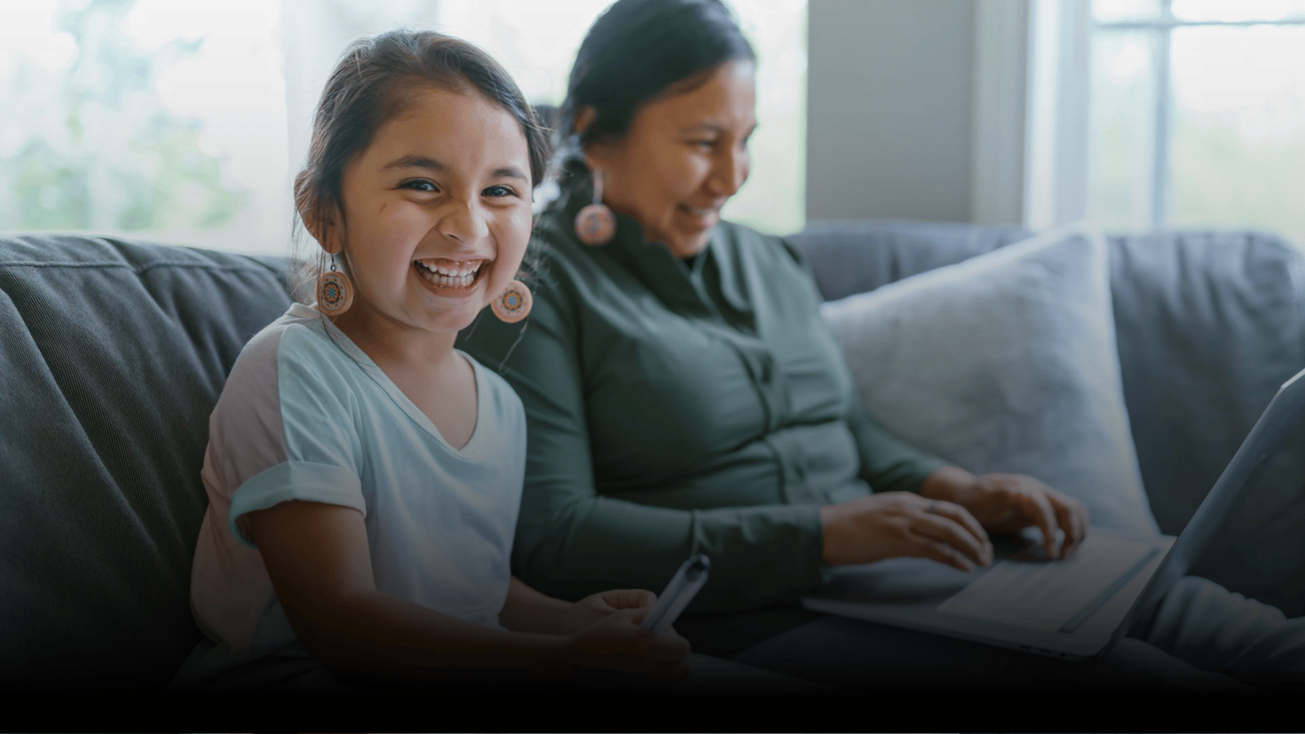 daughter and mother laughing together on couch