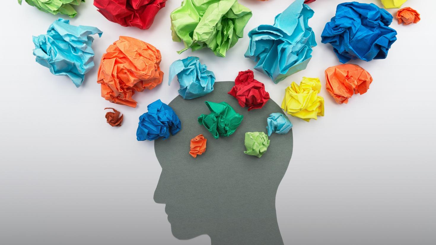 grey shape of head and crumpled up paper of various colours around top of it