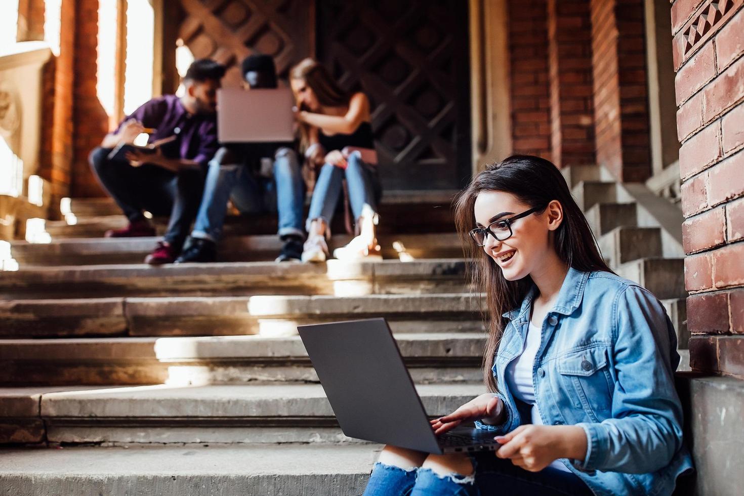 people on steps, one woman smiling while looking at open laptop