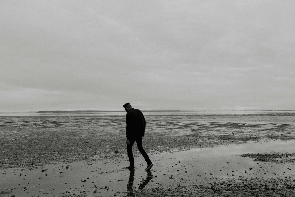 Male figure walking on a beach, moody