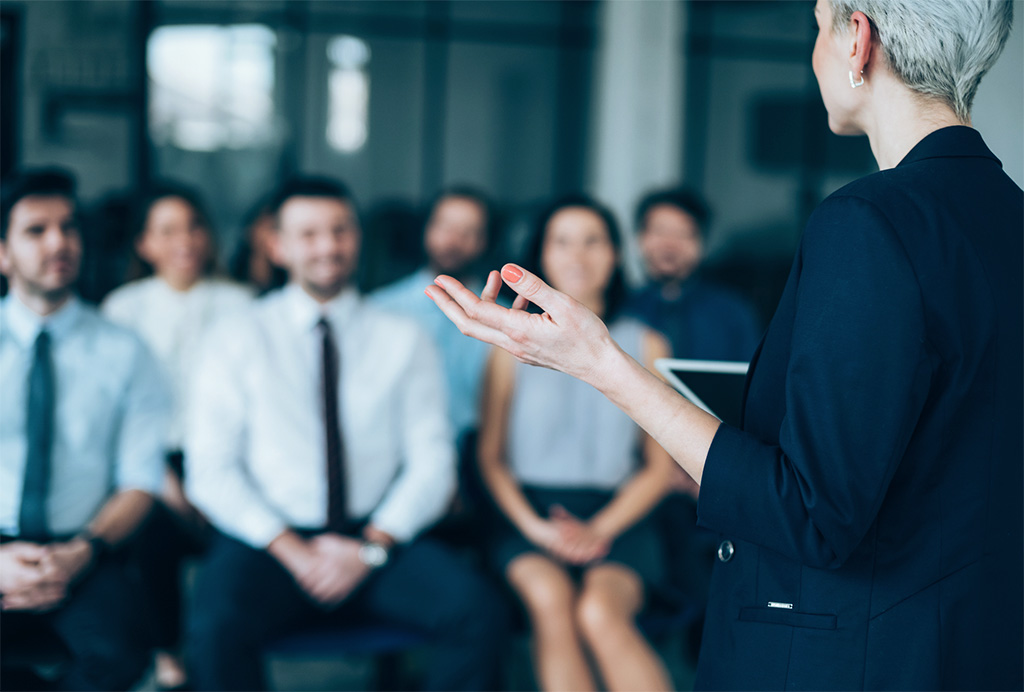 Une femme fait une présentation devant un groupe.