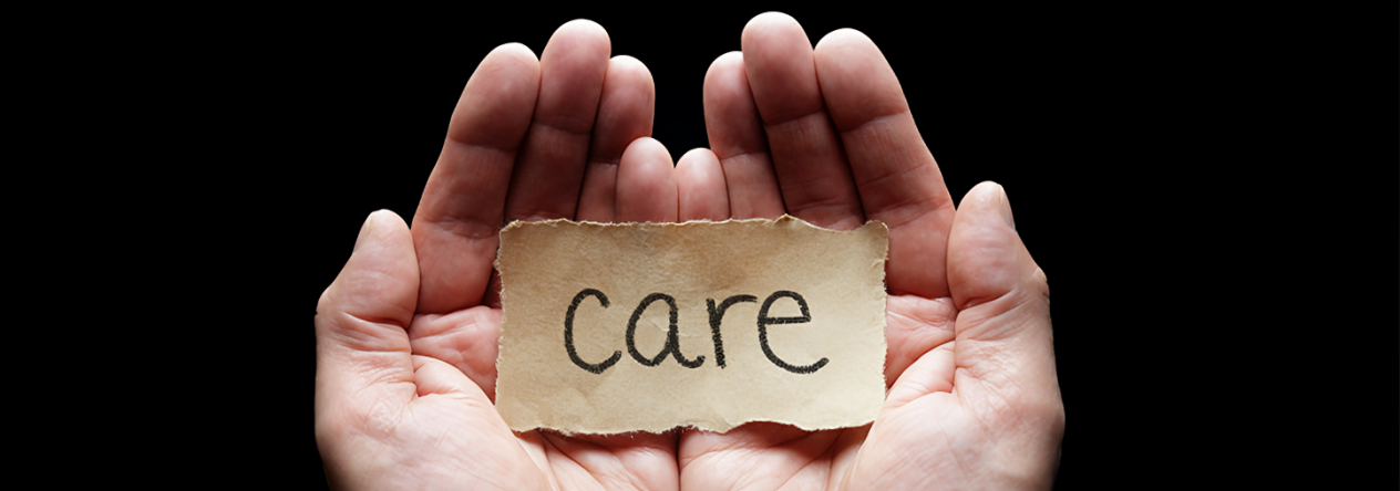Le mot « care » sur un morceau de papier brun, dans une paume de main