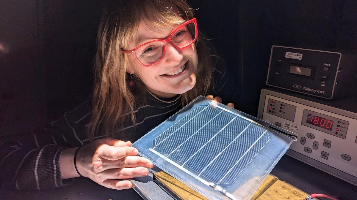 Erin Tonita tenant un panneau solaire dans un laboratoire