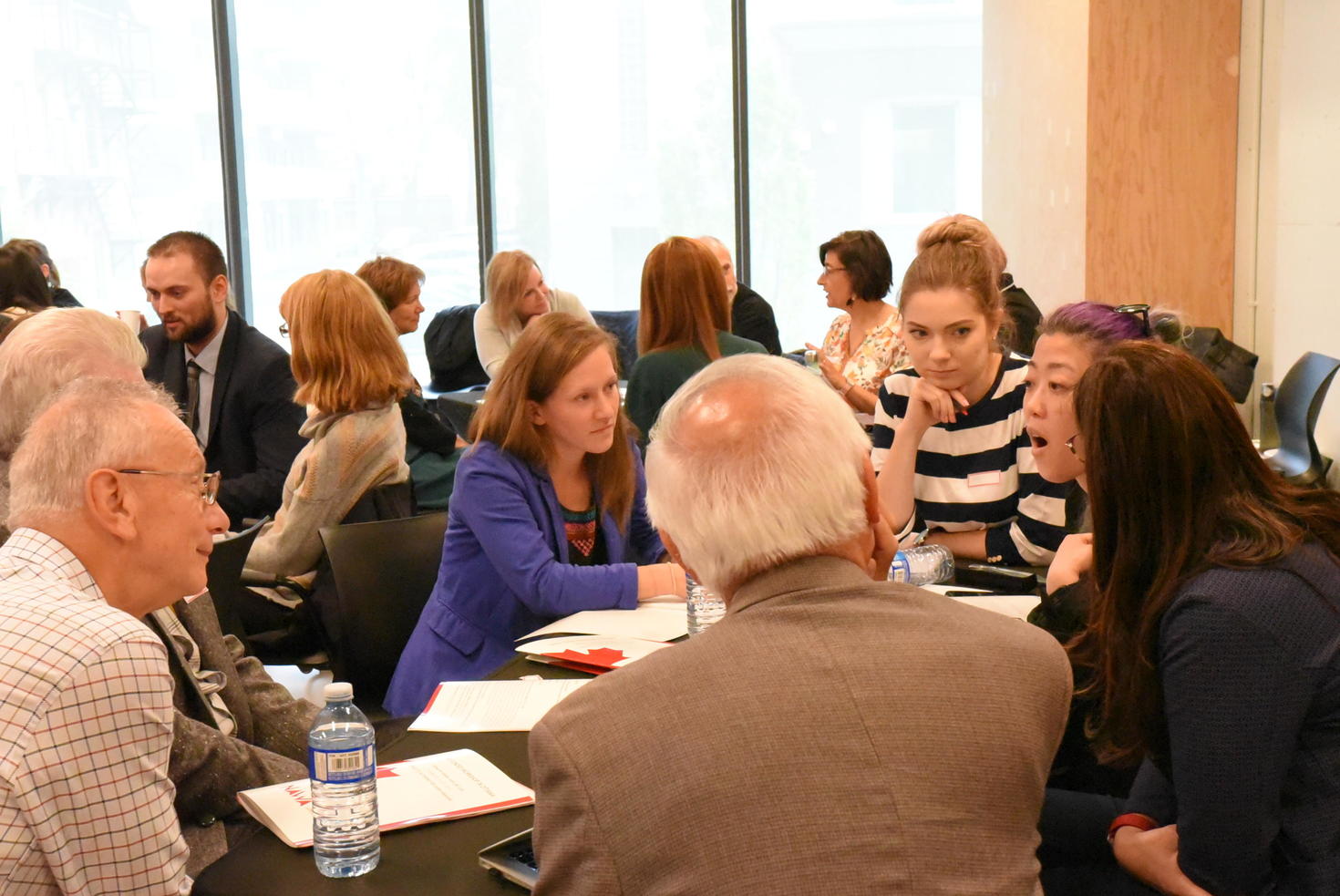 Group of multigenerational people sitting around workshop tables 