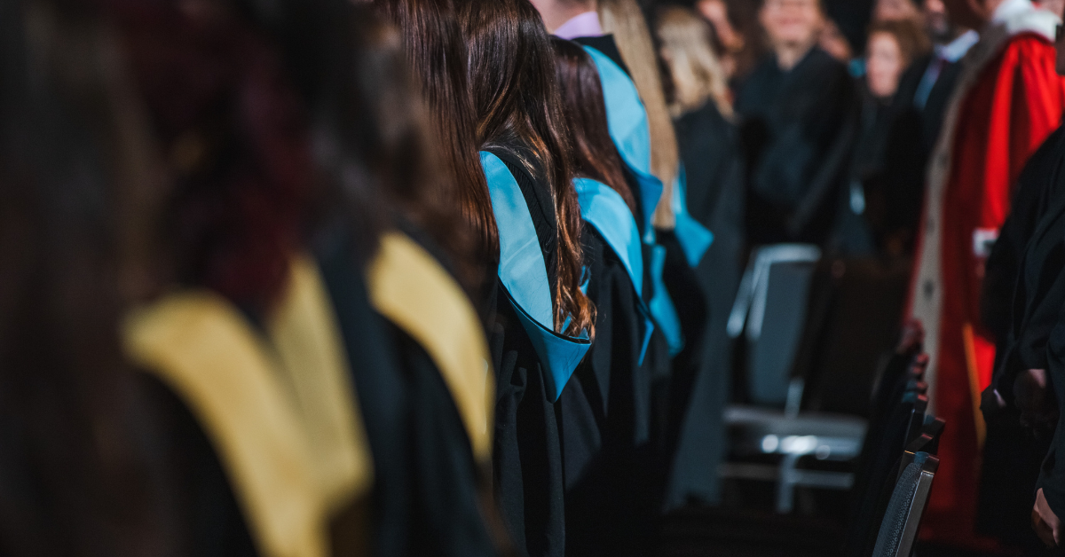 Étudiantes et étudiants de dos portant différentes couleures d'épitoges