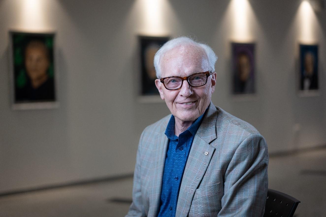 Le professeur Paul Corkum souriant devant le mur d'une galerie. 