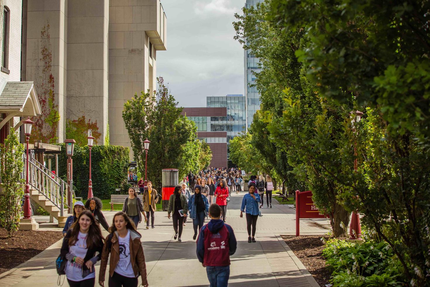 Students walking North on the uOttawa campus with the FSS building in the background.