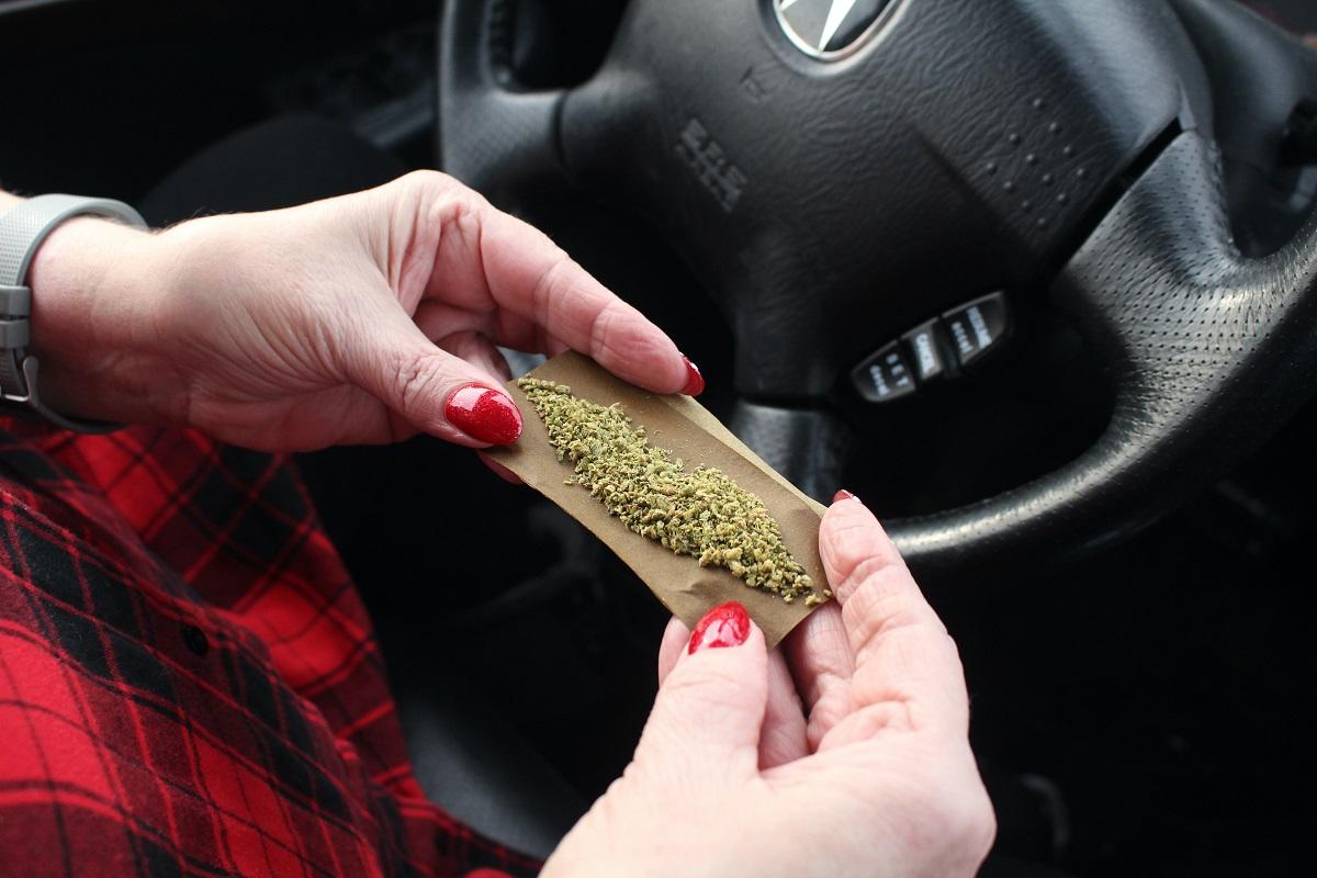 Femme roulant un joint sur le volant d'une voiture