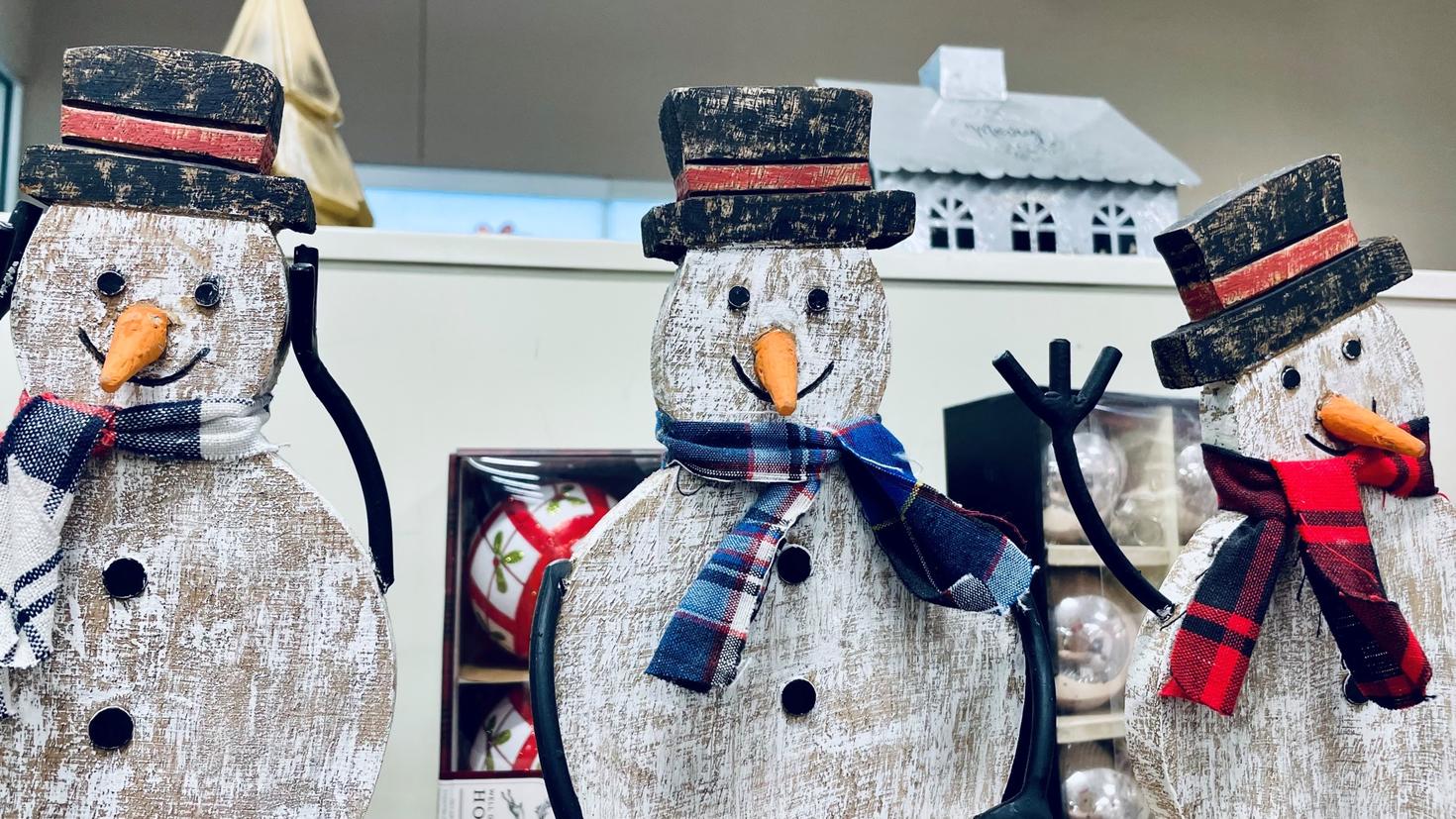 Trois bonhommes de neiges de bois blanc, avec foulards et chapeaux.