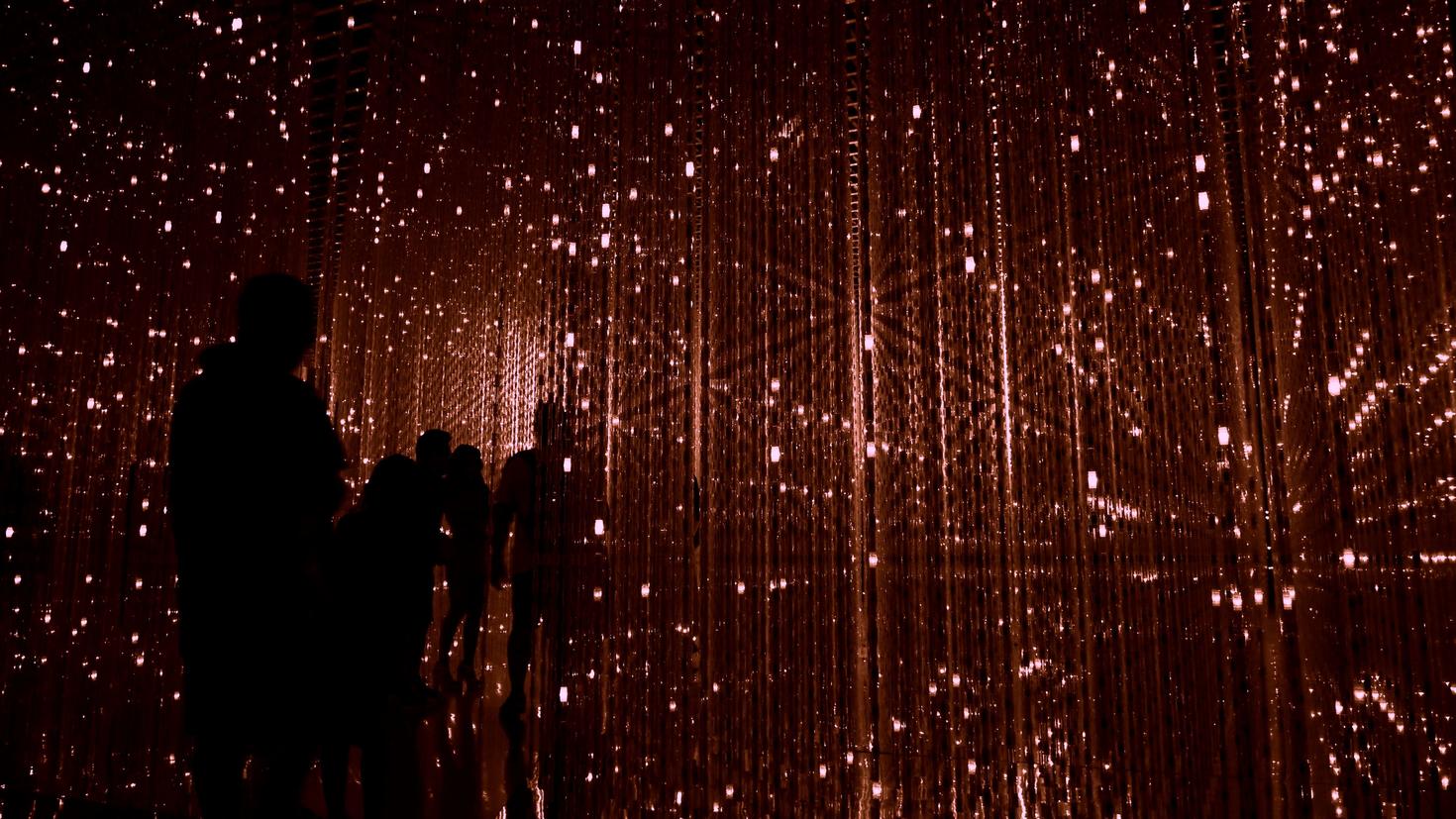 Silhouettes de personnes dans une pièce sombre éclairée par des lumières rouges vives
