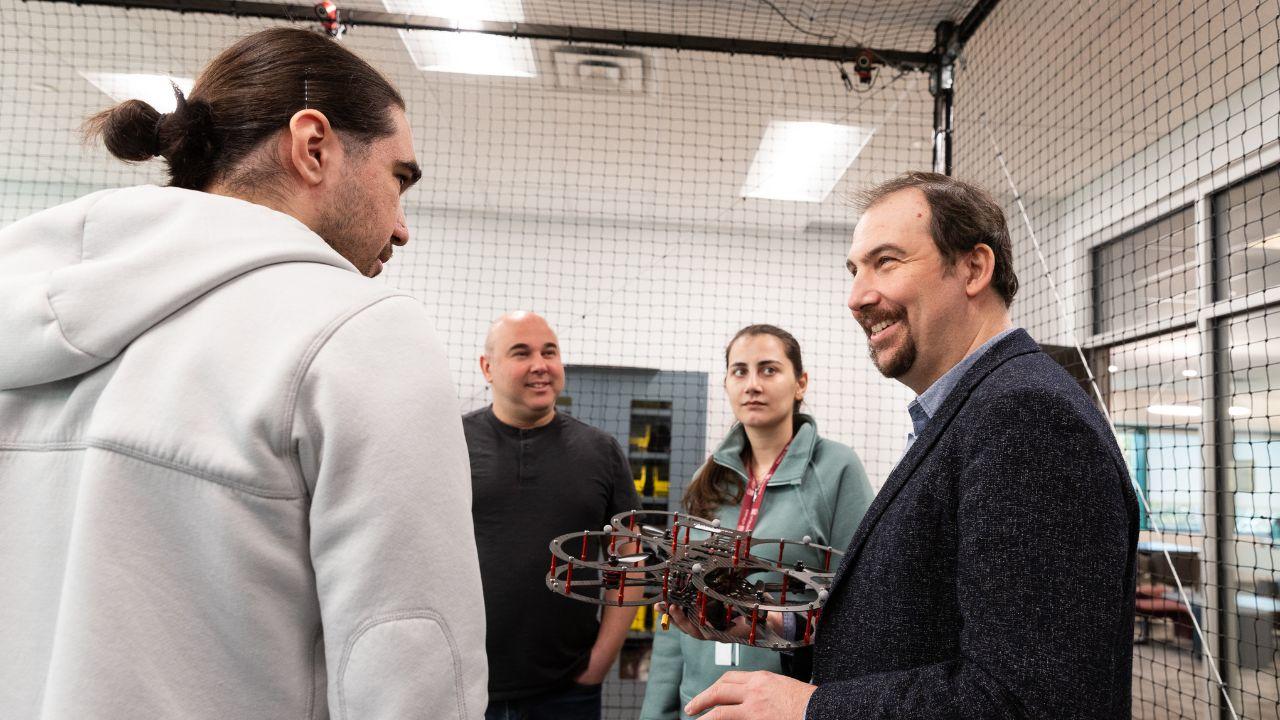 Le professeur Burak Kantarci s'entretient avec des étudiants et tient un drone.
