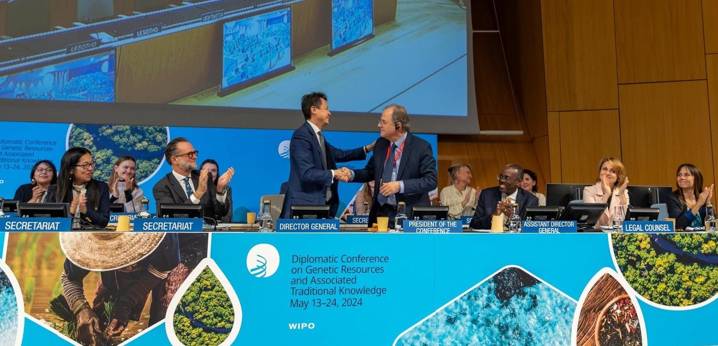 Les délégués à la conférence de l'OMPI applaudissent tandis que deux responsables se serrent la main