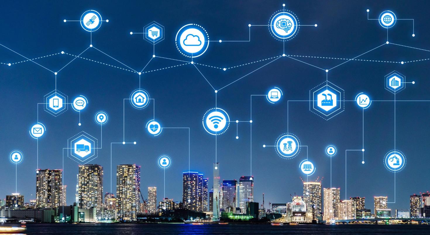 Des symboles d'appareils interconnectés flottent au-dessus d'un horizon urbain.