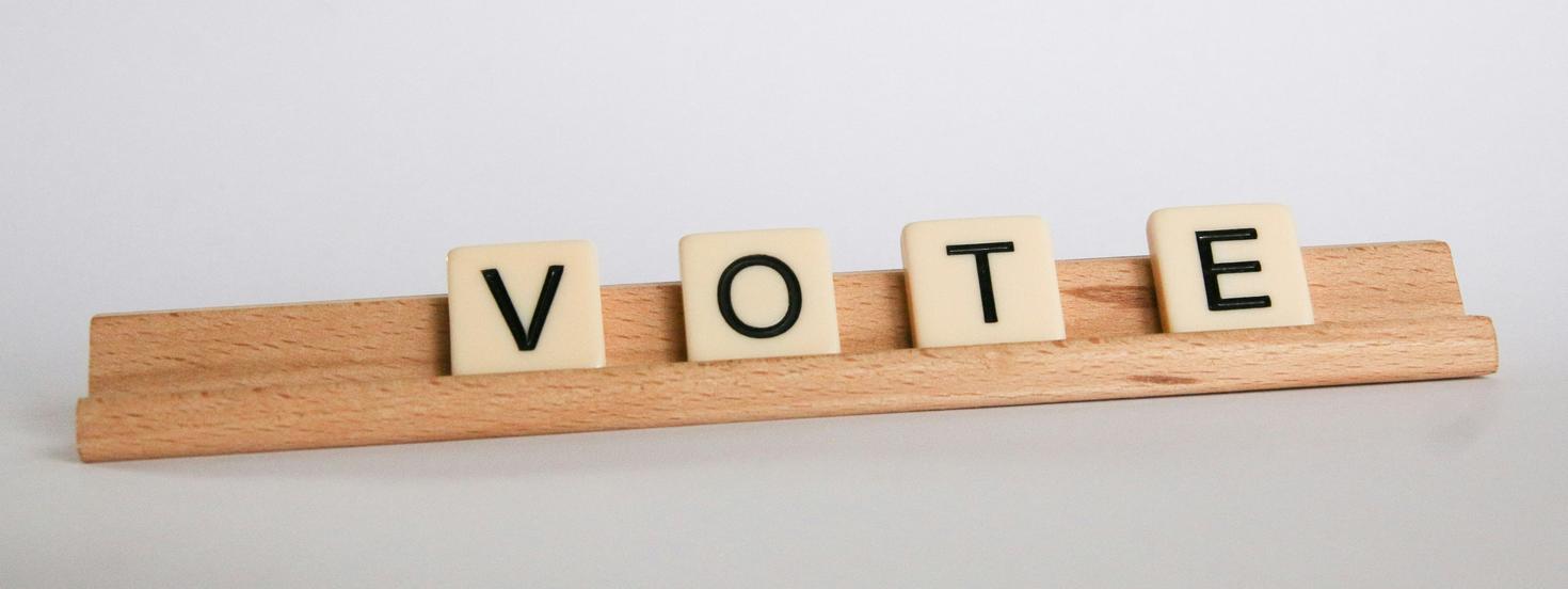 Tuiles de Scrabble formant le mot « VOTE » sur un support en bois