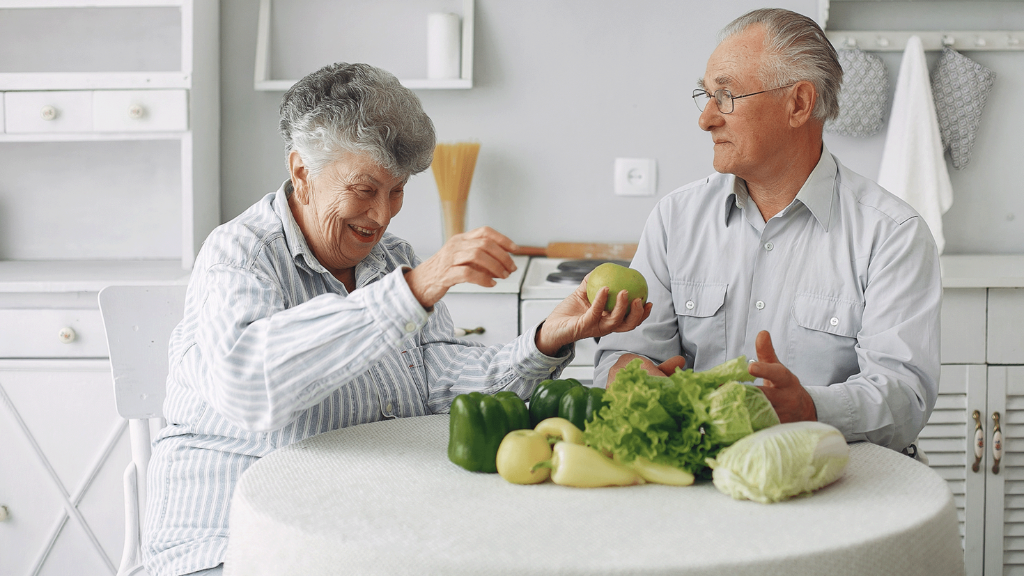 Un couple âgé préparant de la nourriture à la table de la cuisine