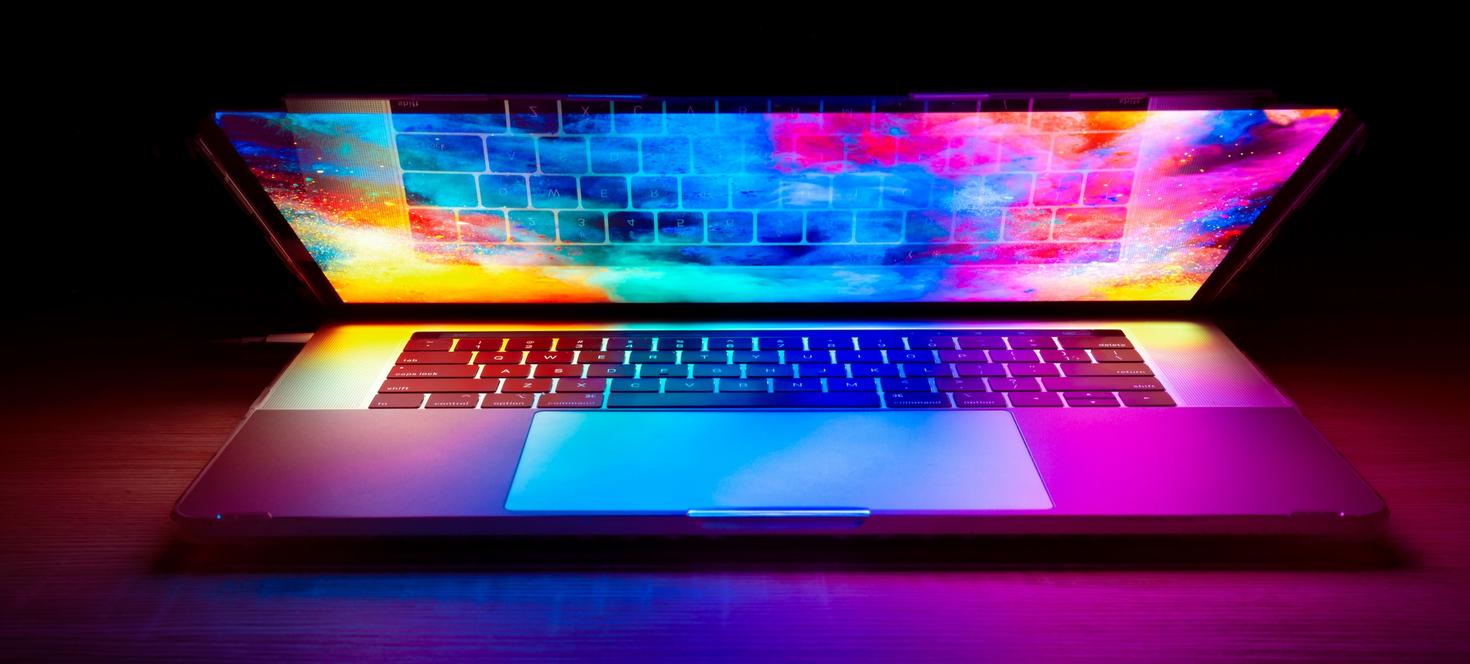 Ordinateur portable partiellement ouvert, éclairé par une lumière colorée