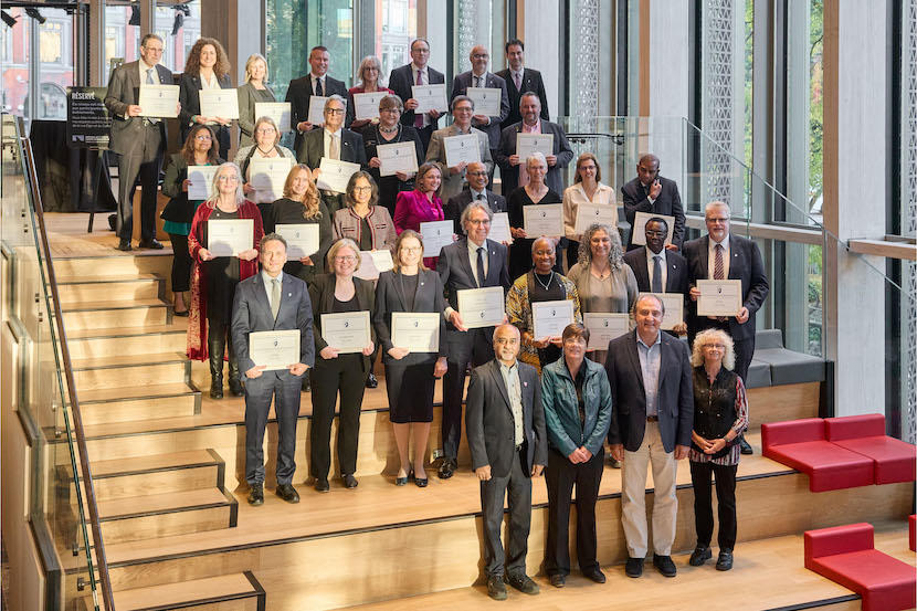 Un groupe de personnes tenant des certificats derrière un groupe de dirigeantes et dirigeants.