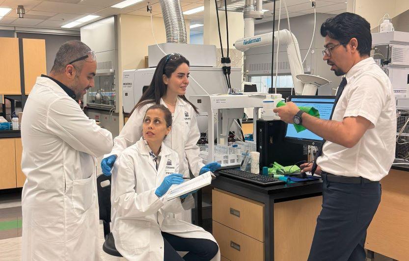 Quatre membres de l’équipe GreenVeil, dont trois en sarrau, se concertent dans un laboratoire.