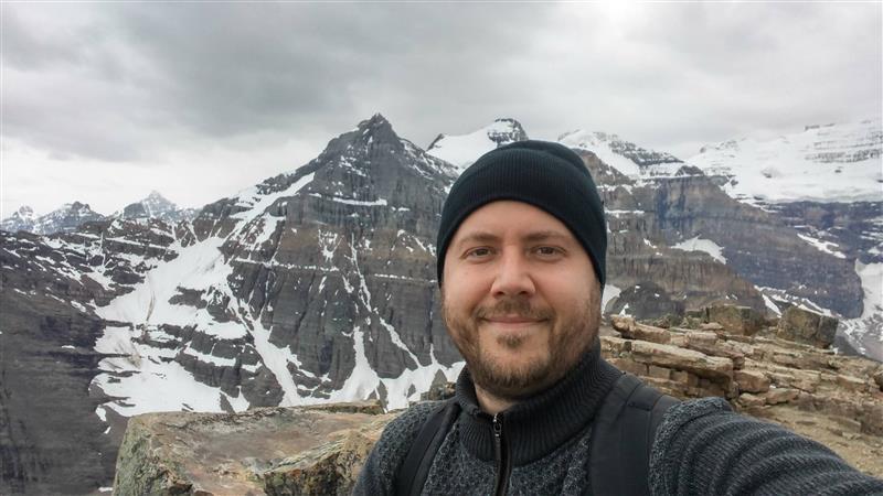 Hugo Begin en randonnée hivernale, prenant un selfie avec des montagnes enneigées