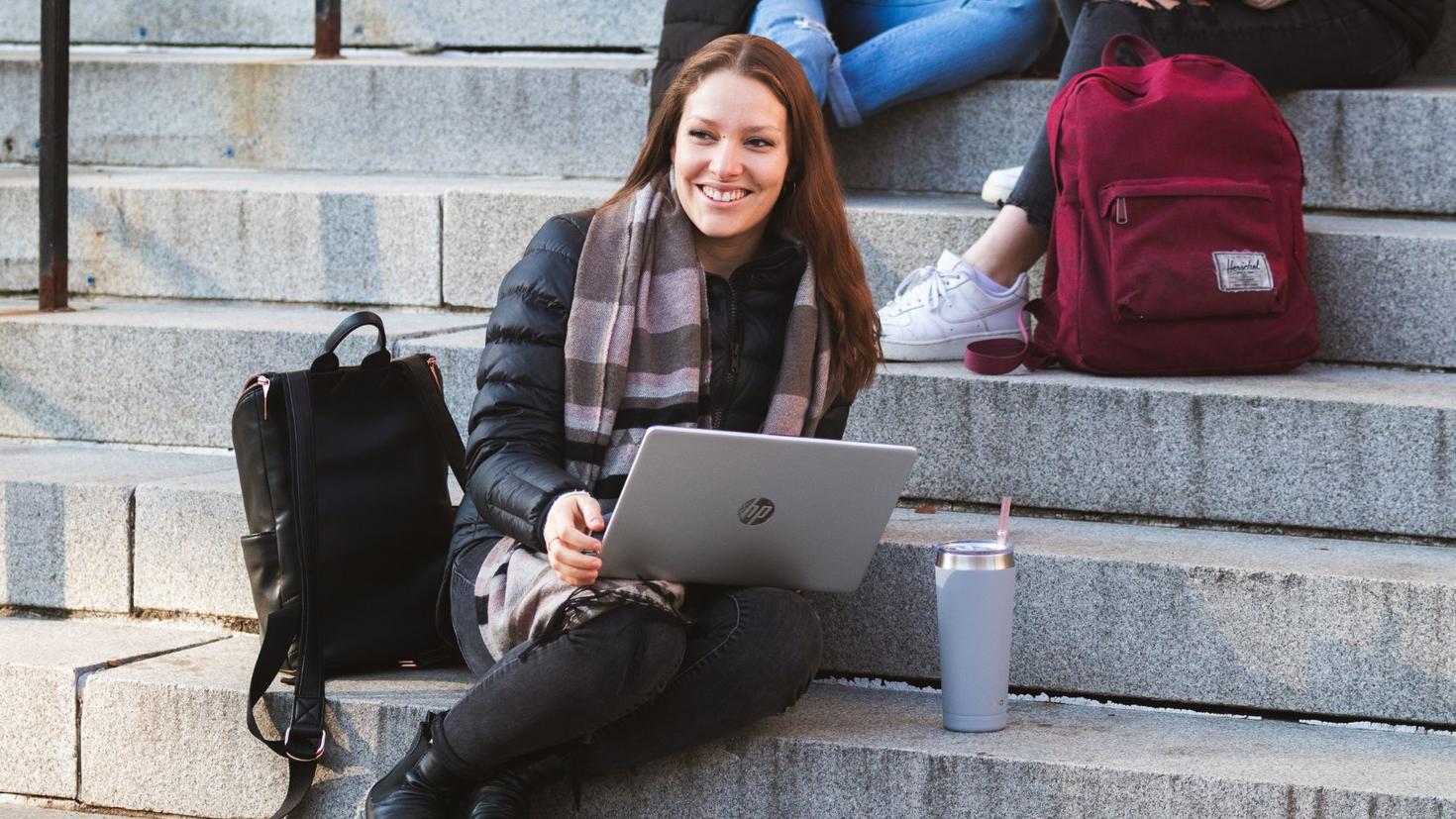 Student sitting on stairs with laptop