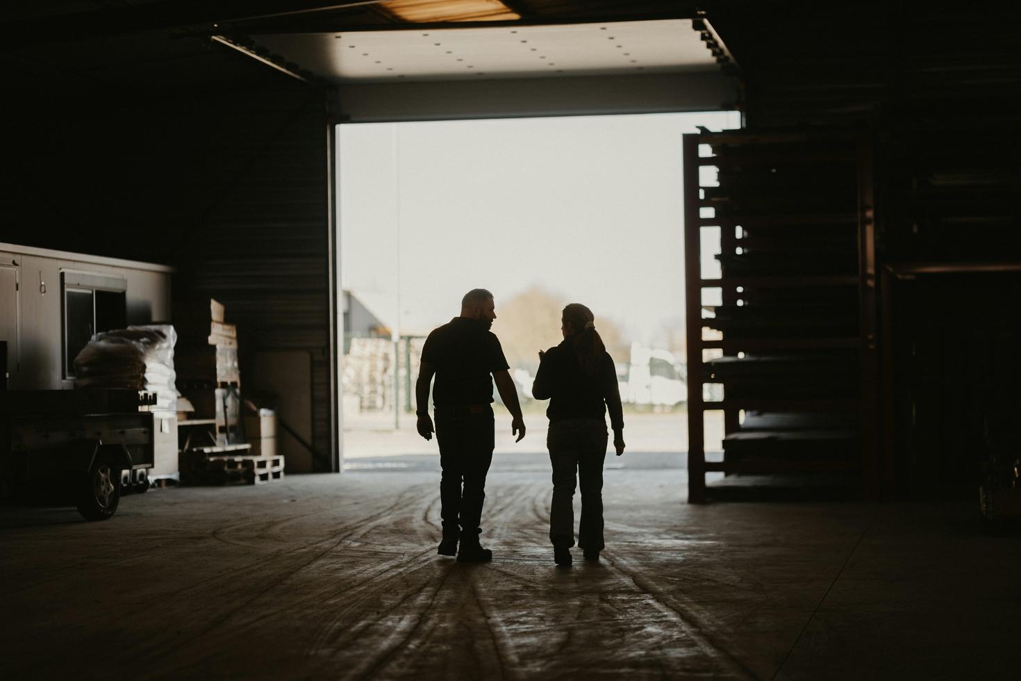 Un homme et une femme marchent ensemble dans un garage industriel.