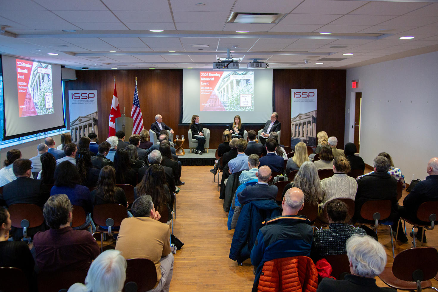 Vue sur le panel de la Conférence commémorative Bromley sur scène et sur le public depuis le fond de la salle