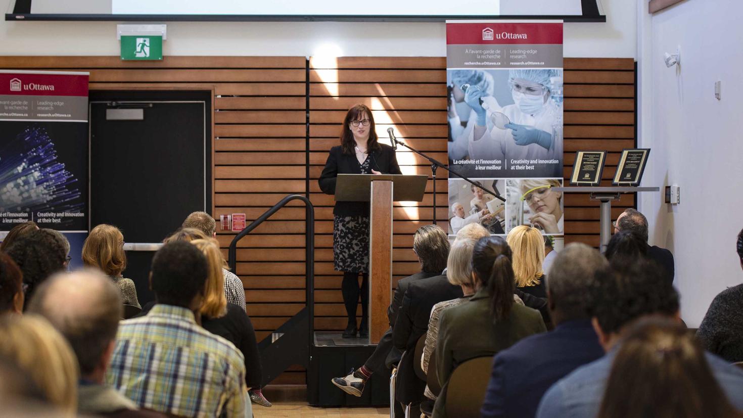 Woman at a podium speaking to an audience