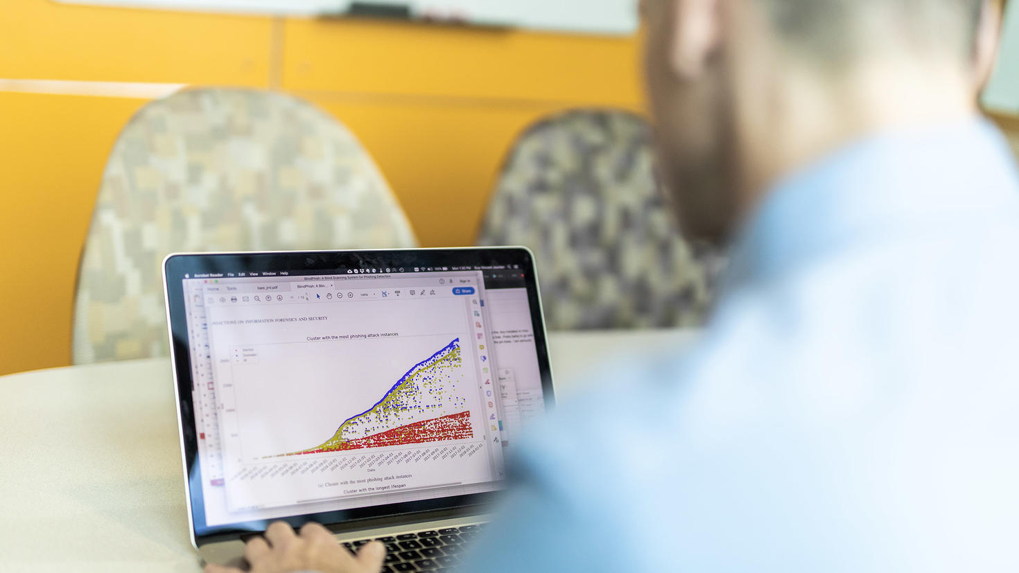 A man looks at a graph presenting data related to cybercrime on a laptop computer.