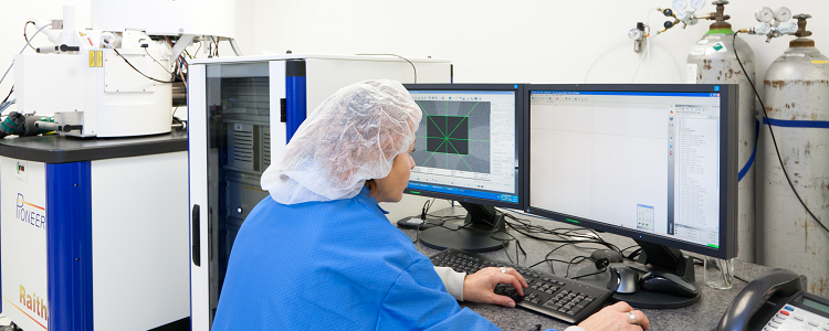 Scientist doing work at a computer wearing a hair net