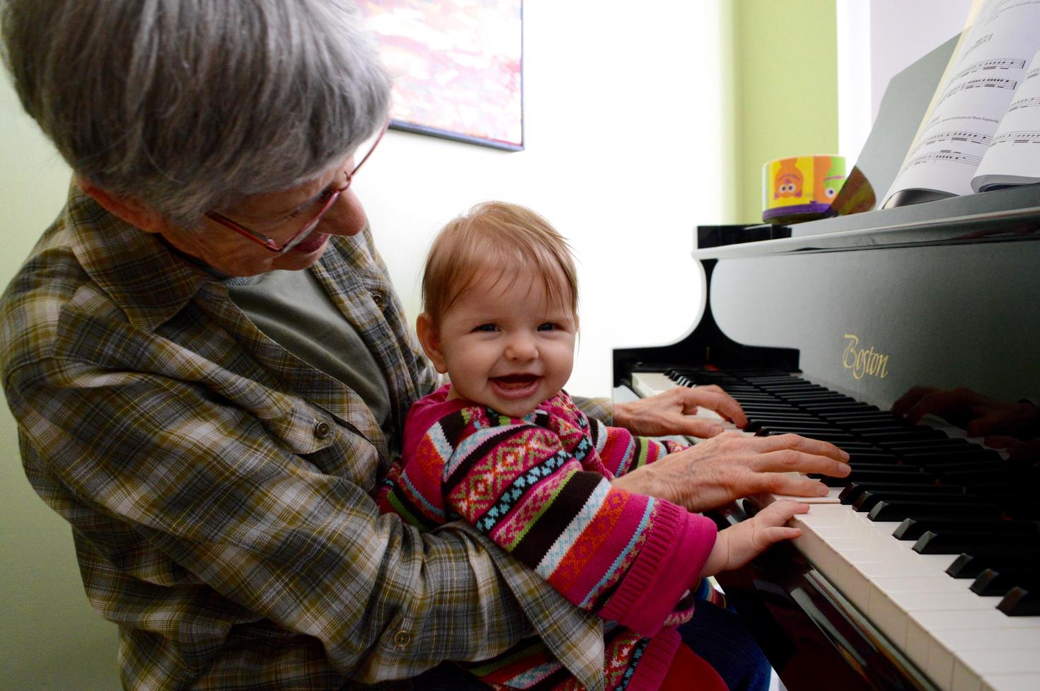 Person sitting at a piano with a baby 