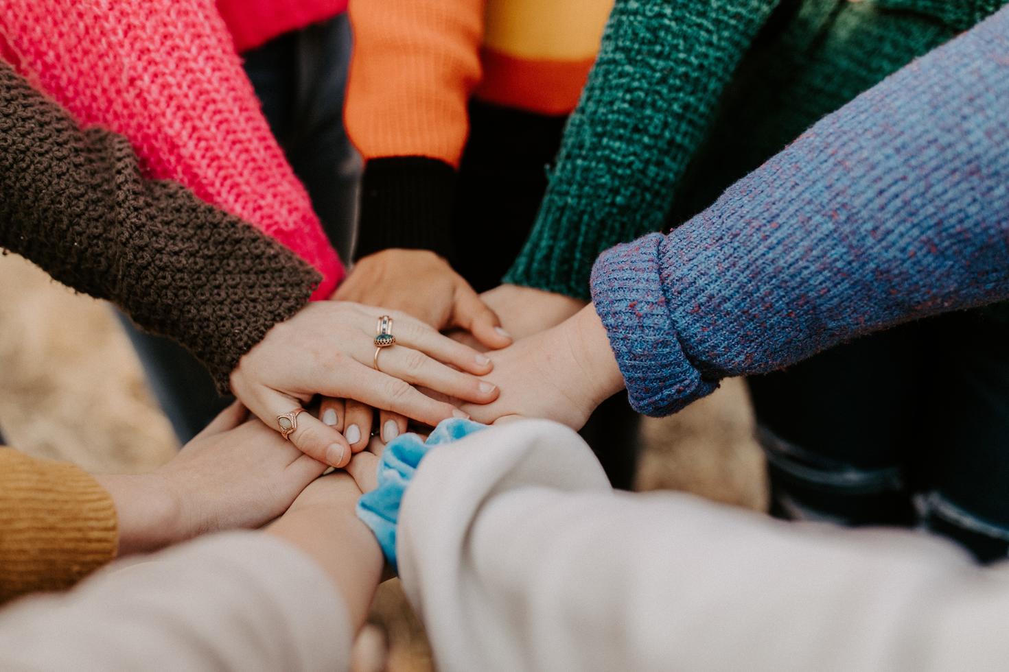 Group of people's hands on top of each other in a circle.