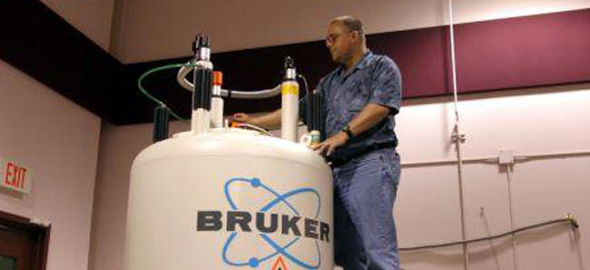 NMR spectroscopist next to an NMR magnet.