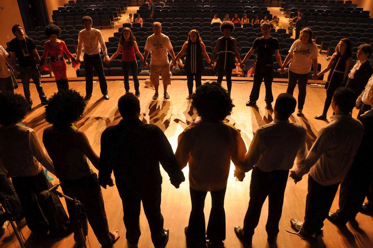Group of people in a circle holding hands on a stage