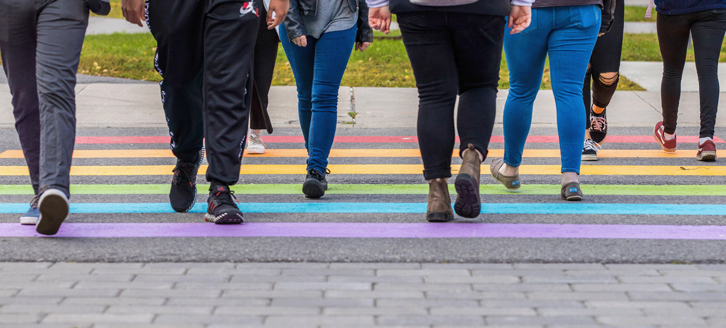 People using a rainbow coloured crosswalk.