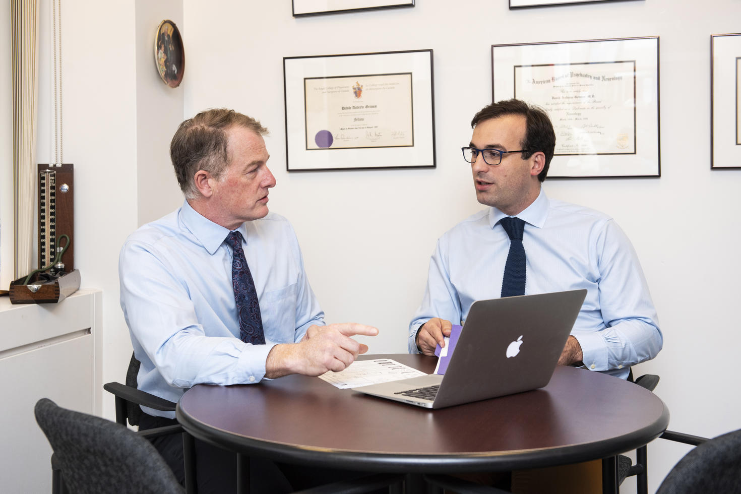 Two researchers sitting at table discussing something with laptop open.